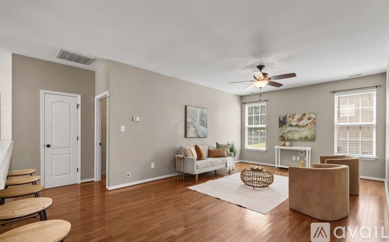 A living room with a white sofa, a wooden coffee table, and a ceiling fan.