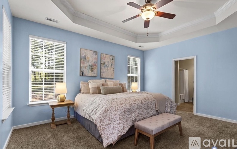 A bedroom with a bed, a bench, and a ceiling fan.