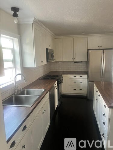 A kitchen with white cabinets and a wooden counter top.