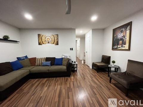 A living room with a brown couch and a painting on the wall.