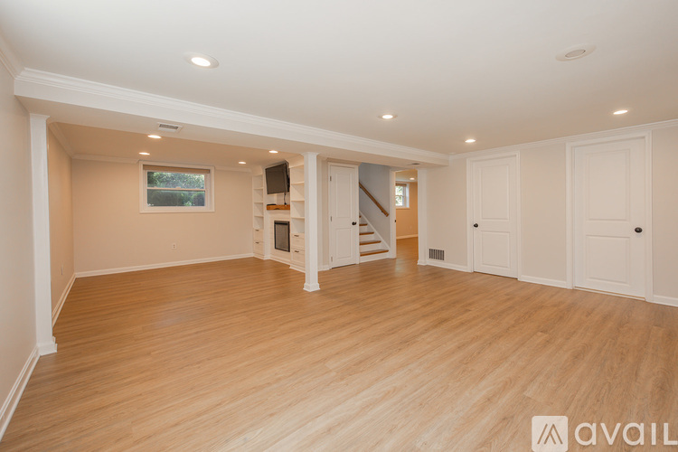 A spacious room with wooden flooring and white walls.