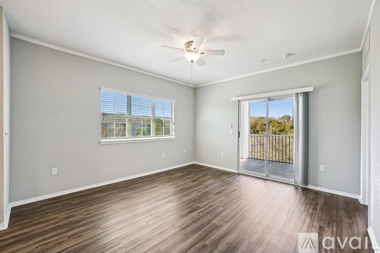 A spacious room with wooden flooring and a sliding glass door leading to a balcony.