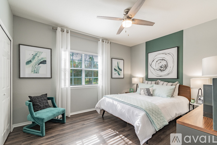 A bedroom with a bed, chair, and artwork.
