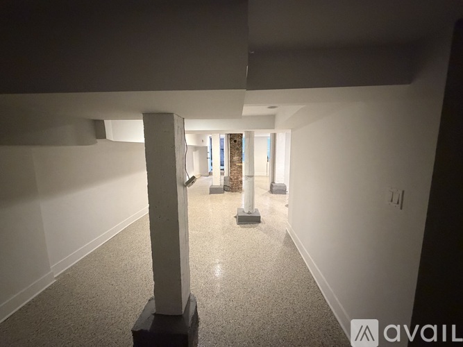 A long white column stands in a room with a carpeted floor.