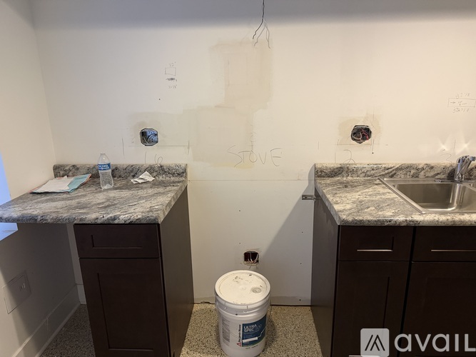 A bathroom with two sinks and a counter top with a container of paint on it.
