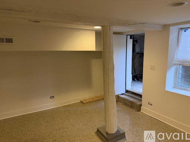 A room with a large pillar and a window on the right side.