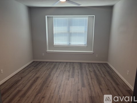 A room with wooden flooring and a window with blinds.