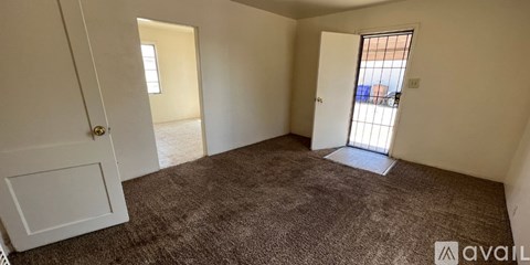 A carpeted room with a door and a window.