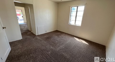 A room with a carpeted floor and a window with a white frame.