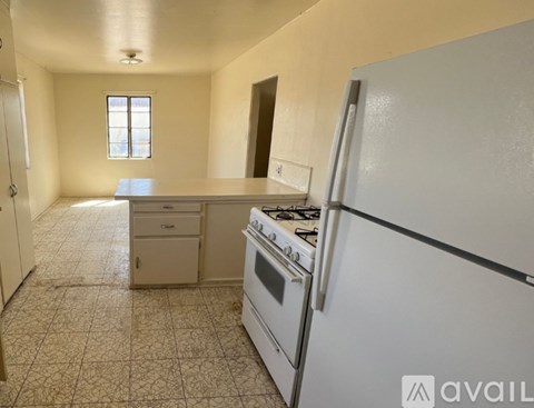 A kitchen with a white refrigerator, a stove, and a window.