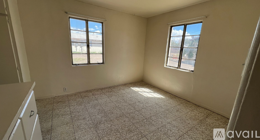 A room with two windows and a tiled floor is available for rent.
