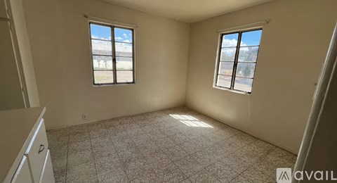 A room with two windows and a tiled floor is available for rent.