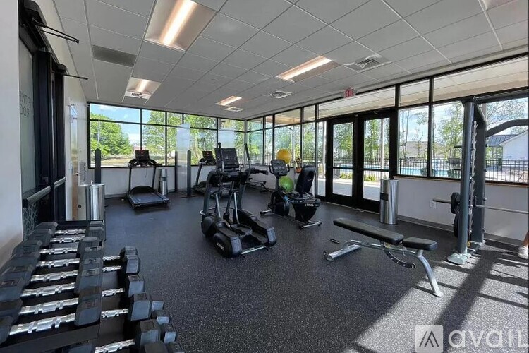 A gym with various exercise equipment and a view of the outside.