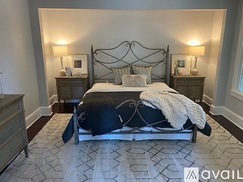 A bedroom with a large bed and two lamps on bedside tables.