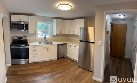 A kitchen with white cabinets and a wooden floor.