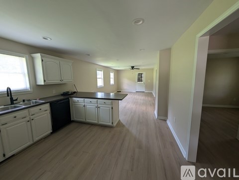 A kitchen with white cabinets and a wooden floor.
