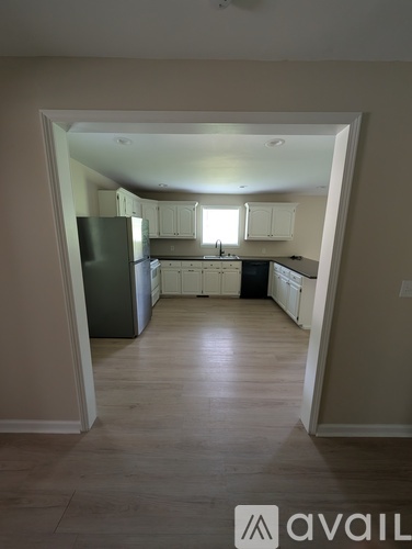 A kitchen with white cabinets and a black fridge is shown.
