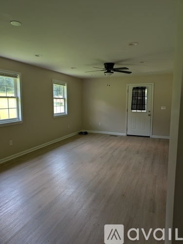 A room with a ceiling fan and wooden flooring.
