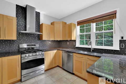 A kitchen with wooden cabinets and a black speckled backsplash.