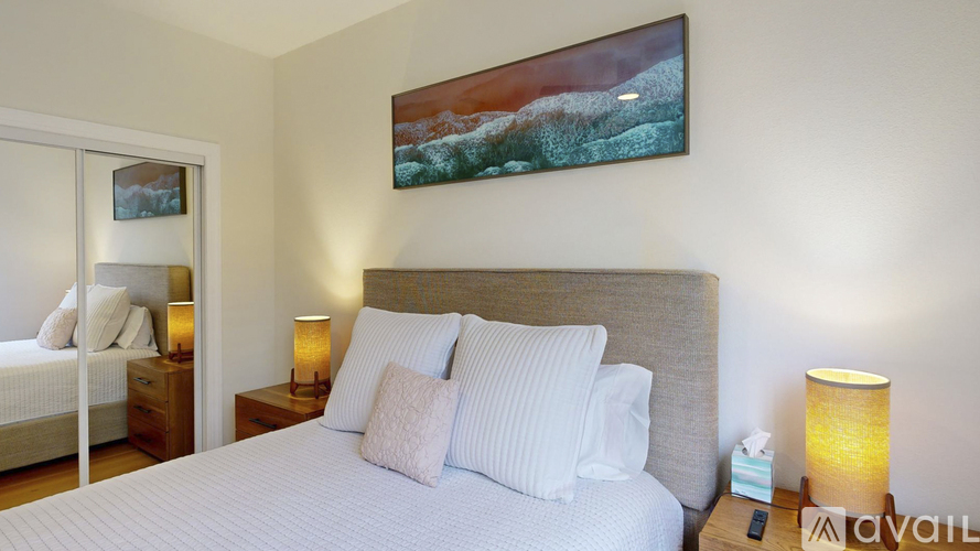 A bedroom with a large bed and a painting on the wall.