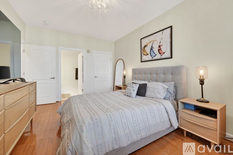 A bedroom with a large bed, a wooden nightstand, and a chandelier.