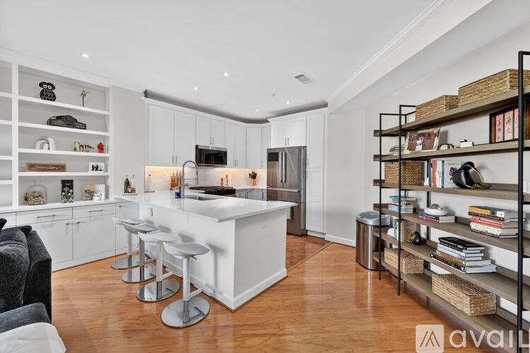 A modern kitchen with white cabinets and a wooden floor.