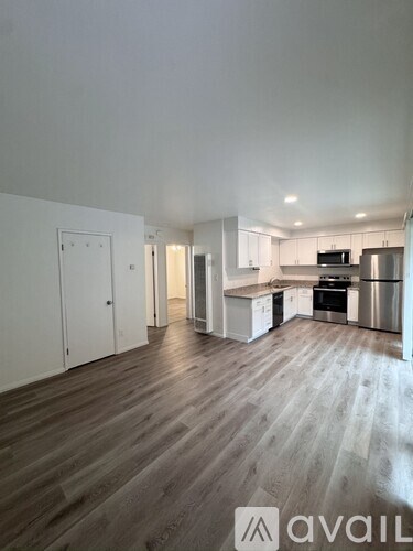 A spacious kitchen with white cabinets and a wooden floor.