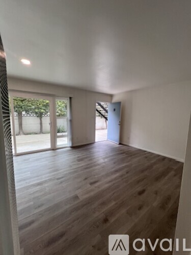 A room with wooden flooring and a sliding glass door leading outside.