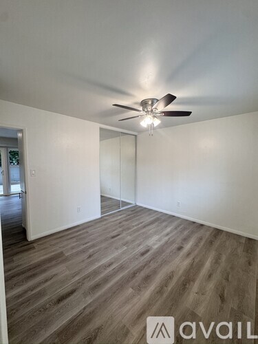 A room with a ceiling fan and wooden flooring.