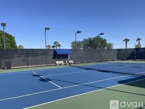 A tennis court with a blue roof and white lines.