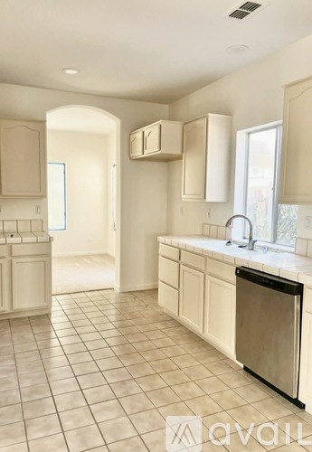 A kitchen with white cabinets and a black dishwasher.