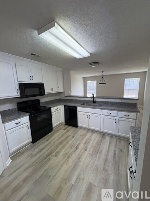 A kitchen with white cabinets and a black stove top oven.