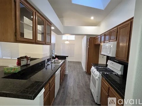 A kitchen with black countertops and white appliances.