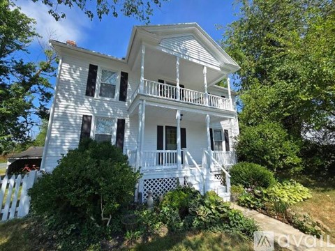A white house with a balcony and a porch.