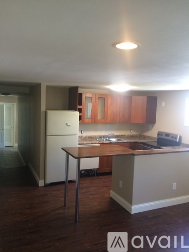 A kitchen with wooden floors and a white refrigerator.