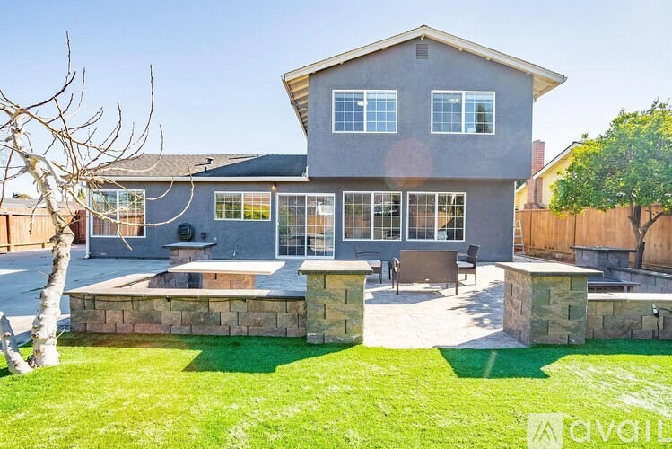 A house with a grey exterior and a stone wall in the front yard.