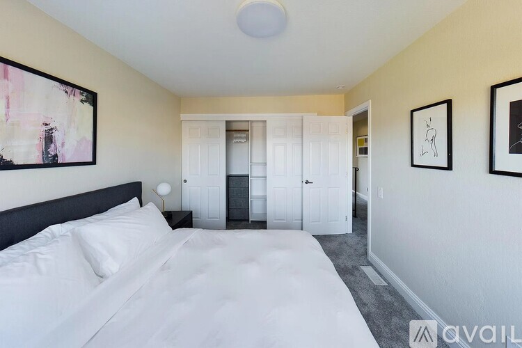 A bedroom with a large bed and two framed pictures on the wall.