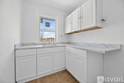 A kitchen with white cabinets and a marble countertop.