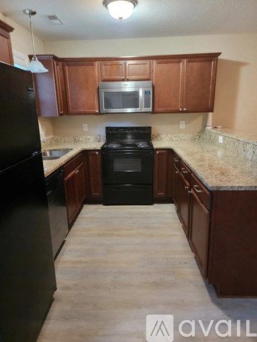 A kitchen with black appliances and wooden cabinets.