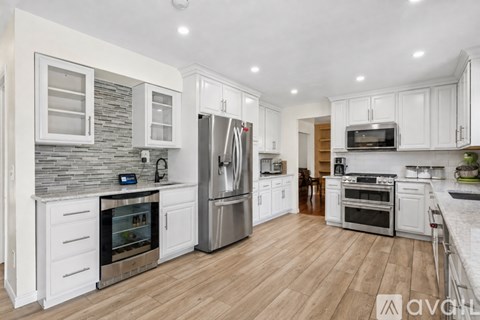 A modern kitchen with white cabinets and wooden floors.