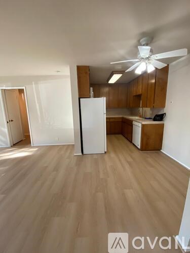 A kitchen with wooden floors and a white refrigerator.