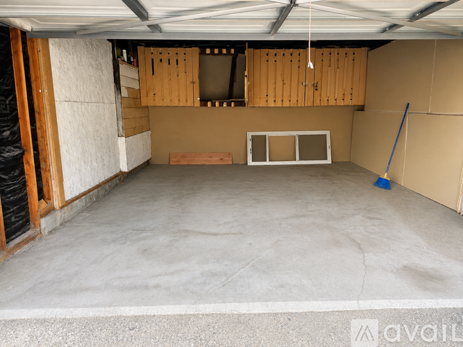 A spacious garage with a white floor and wooden cabinets.