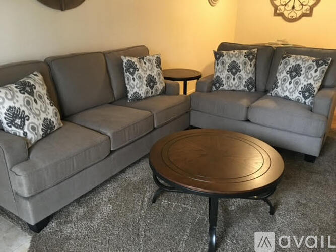 A grey sofa with a wooden coffee table in front of it.