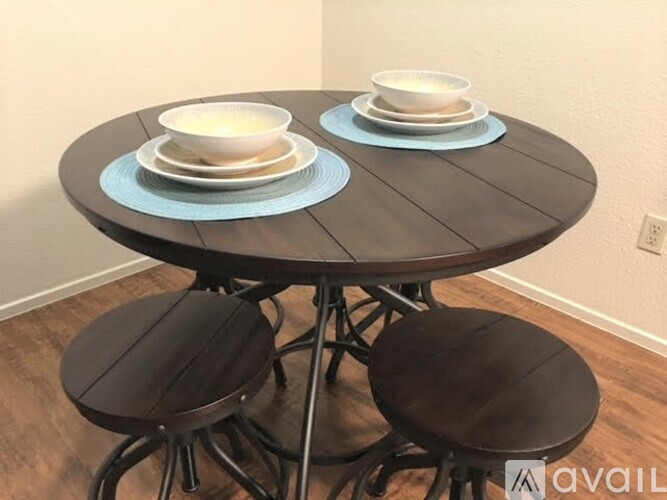 A round wooden table with two stools and plates on it.