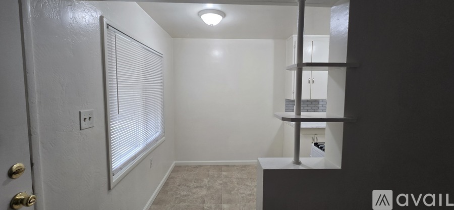 A small room with a door, a shelf and a light on the ceiling.