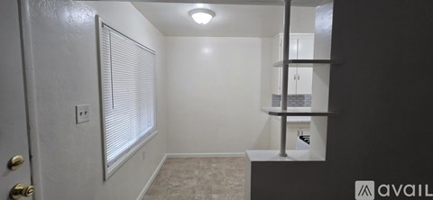 A small room with a door, a shelf and a light on the ceiling.
