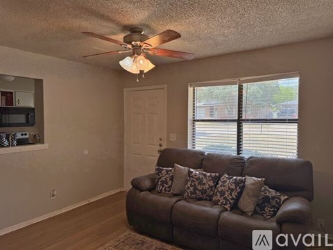 A living room with a brown couch and a ceiling fan.