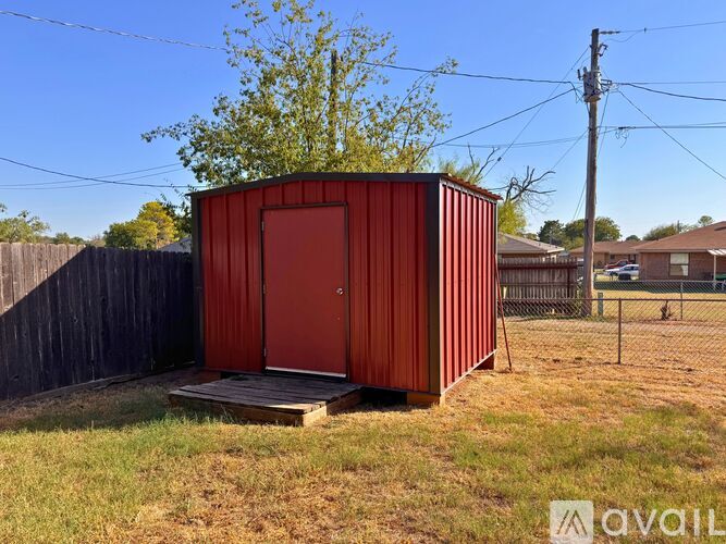 A red shipping container sits in a grassy field.