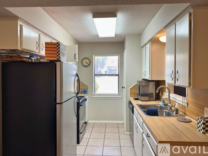 A kitchen with a black refrigerator and a wooden counter top.