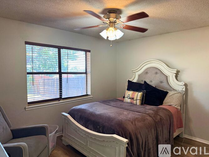 A bedroom with a bed, chair, and window.